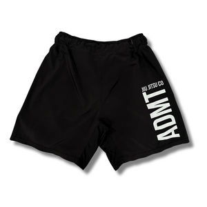 Rear view of Adamantium BJJ black fight shorts featuring white "ADMT Jiu Jitsu Co" branding on the right leg.
