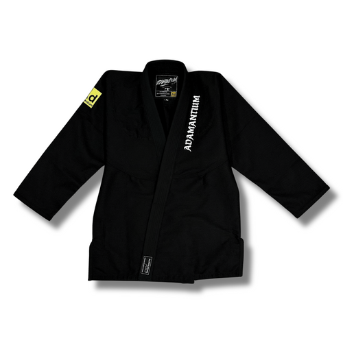 Black Adamantium BJJ Gi – front view, featuring 420GSM pearl weave jacket with embroidered branding on the lapel and a yellow patch on the left sleeve.