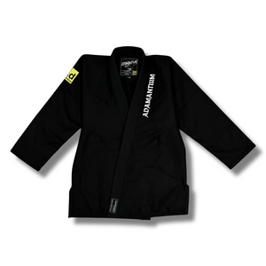 Black Adamantium BJJ Gi – front view, featuring 420GSM pearl weave jacket with embroidered branding on the lapel and a yellow patch on the left sleeve.