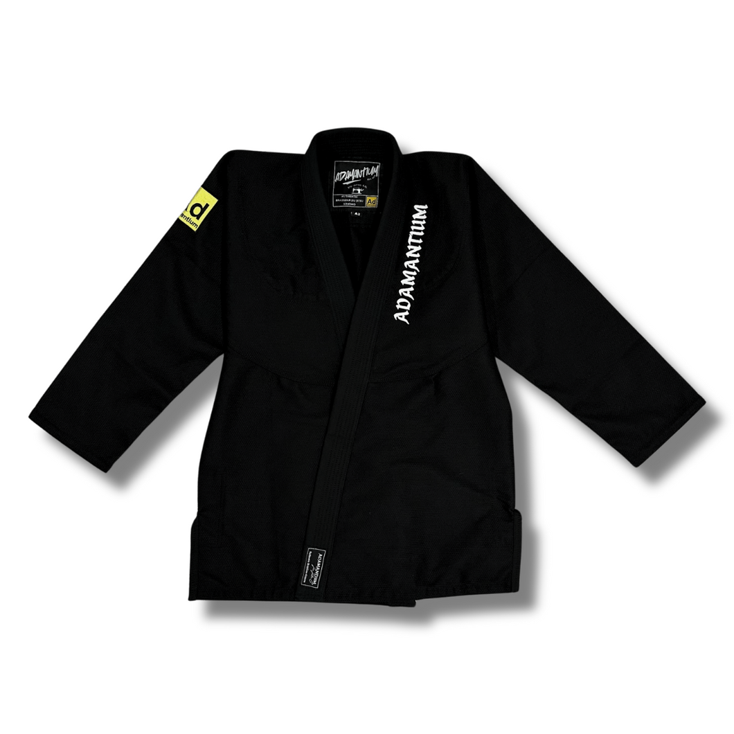 Black Adamantium BJJ Gi – front view, featuring 420GSM pearl weave jacket with embroidered branding on the lapel and a yellow patch on the left sleeve.